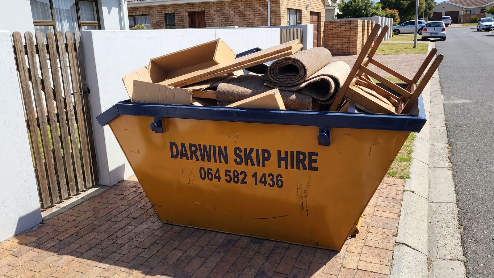 Darwin mini skip loaded with broken shelving, carpet and a chair from a garage clean-out.