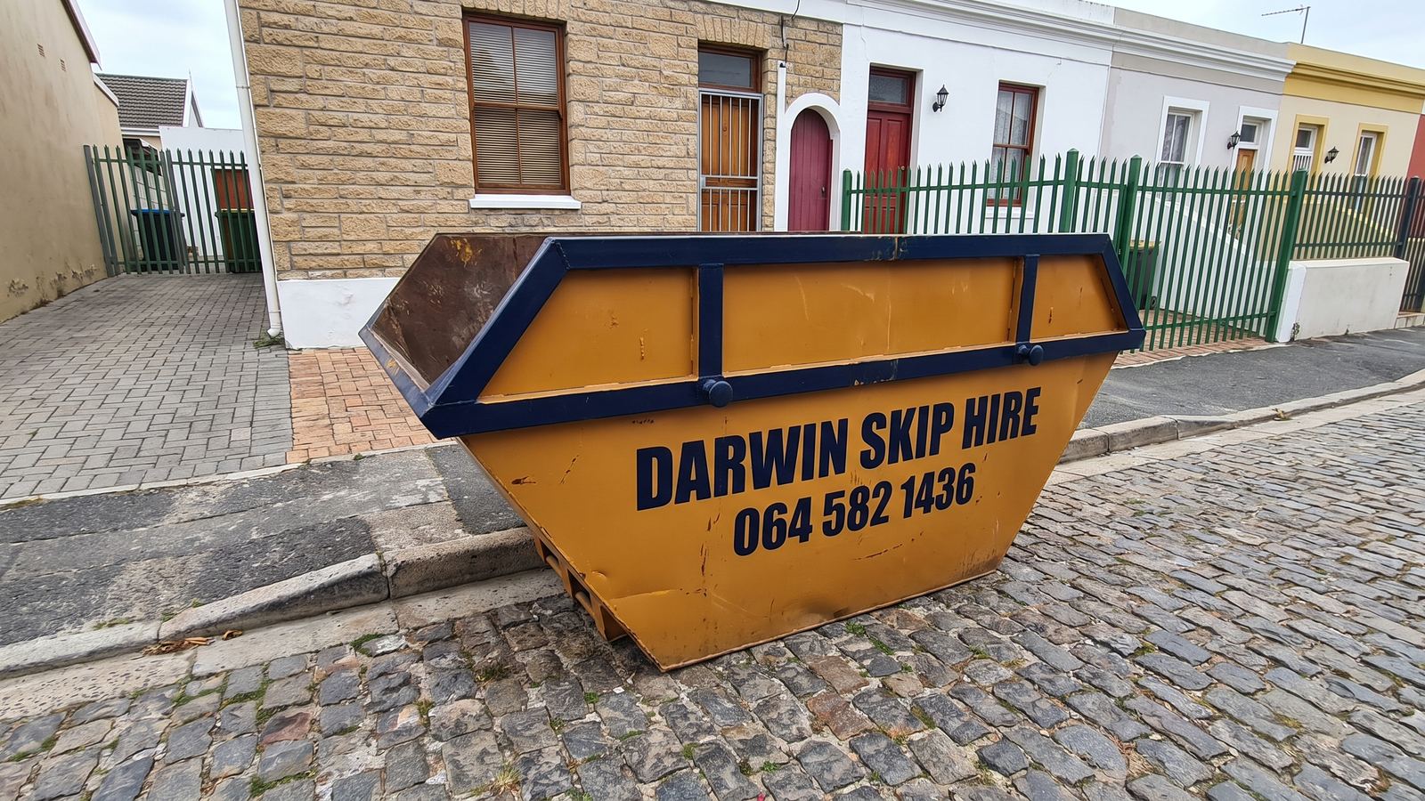 Amber Darwin mini skip on a cobbled street in front of terraced houses.
